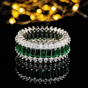 Makroaufnahme eines Luxus-Silberrings mit grünen Edelsteinen und weißen Diamanten