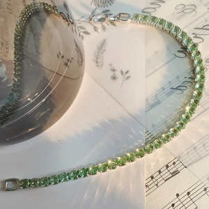 Elegante bracciale tennis verde menta con finitura argento su spartito musicale