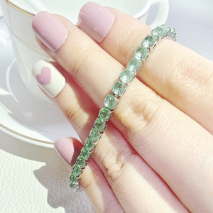 Elegante bracciale tennis con gemme verde menta in argento, indossato da una donna