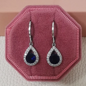 Détail de boucles d'oreilles argentées avec pierres bleues dans une boîte en velours rose