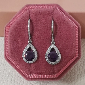 Vue détaillée des boucles d'oreilles goutte avec pierre violette dans un écrin en velours