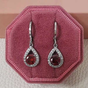 Gros plan de boucles d'oreilles larmes rouges avec cristaux dans un écrin rose
