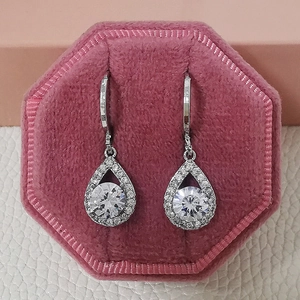 Vue détaillée de boucles d'oreilles goutte pavées avec pierre ronde dans un écrin rose