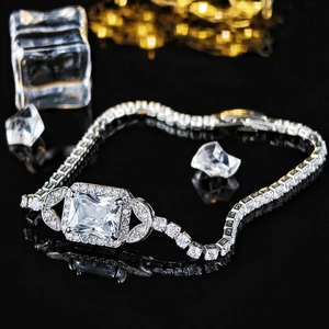 Macro shot of silver tennis bracelet featuring a large square-cut cz stone on black surface