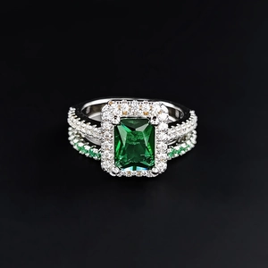 Luxuriöser Ring mit smaragdgrünem Edelstein in Silber mit Diamant-Halo auf schwarzem Grund