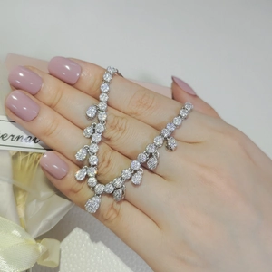 Detailed view of silver necklace with teardrop zircons worn on hand for luxury event