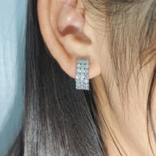 Vue détaillée des boucles d'oreilles C argentées avec double rangée de pierres