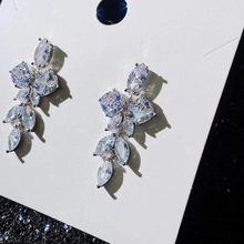 Detail van de zilveren oorbel met bloemcluster van marquise en vierkante zirkonen