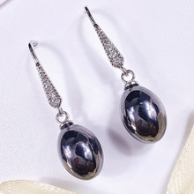 Detail van elegante zilveren hangoorbellen met pavé-driehoek en donkergrijze metalen kraal