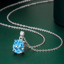 Close-up of a pear-shaped light blue gemstone necklace with silver four-prong setting