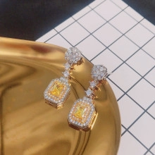 Dettaglio di orecchini in zircone giallo taglio smeraldo con perno a fiore e alone lucente