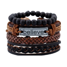 Detail van een meerlaagse lederen armbandset met gegraveerde believe-metalen plaat
