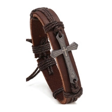 Detailweergave van vintage leren armband met donker metalen kruis en gegraveerde tekst