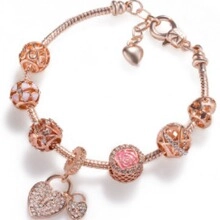 Macro-opname van roségouden slangenarmband met roze bloemen en hartvormige bedeltjes