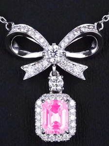 Macro view of emerald-cut pink gemstone pendant with sparkling zircon bow tie details