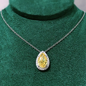 Elegant pear cut yellow gemstone necklace with halo diamond border on velvet stand
