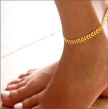 Close-up of a gold metal fishbone anklet worn on the ankle for fashion jewelry