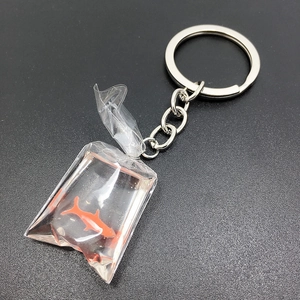 Macro detail of a creative goldfish in water bag keychain with polished silver ring