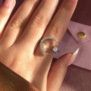 Bague ouverte lune en argent avec zircons étincelants sur main devant sac rose