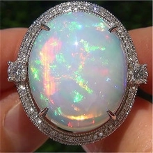 Macro shot of halo opal ring with radiant colorful fire and sparkling zircon accents
