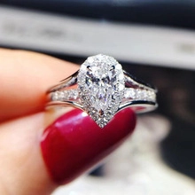 Close-up of a pear-cut blue topaz ring with a halo setting and split diamond band