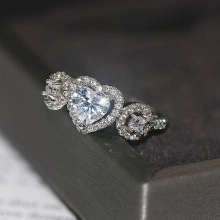 Vista macro de un anillo de corazón de plata con halo de circonitas y pavé lateral