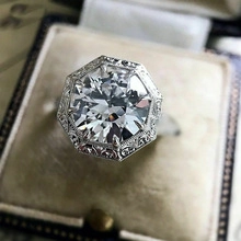 Primer plano de anillo vintage con circonita, grabados y halo octogonal en su estuche