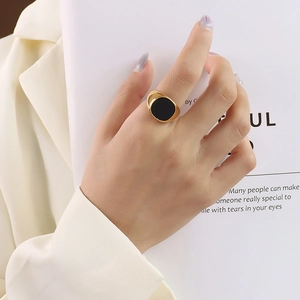 Minimalist gold signet ring with black round inlay shown on hand for women