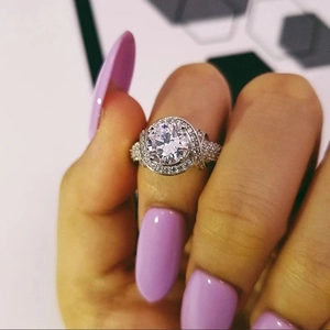 Exquisito anillo halo de plata con piedra redonda central y banda de pavé en mano