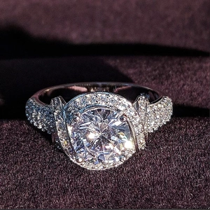 Bague halo luxueuse avec pierre ronde brillante et anneau pavé sur fond de velours