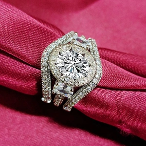 Elegante conjunto de tres anillos halo con circonitas sobre lujosa tela de raso rojo rosa