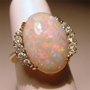 Elegant gold oval opal ring featuring vibrant fire colors and sparkling side diamonds