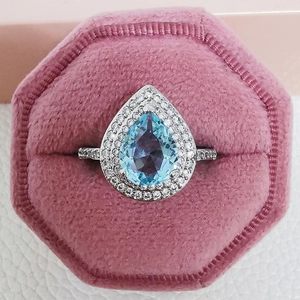 Luxury pear-cut blue topaz ring with double halo diamond pavé in a velvet jewelry box