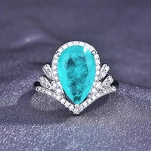 Makroaufnahme eines silbernen V-förmigen Kronenrings mit türkisfarbenem Stein und Zirkon