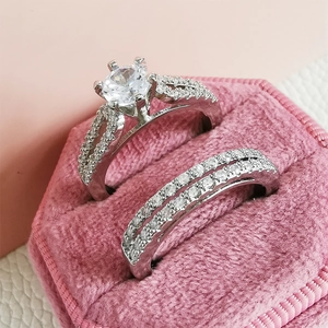 Detailed close-up of a silver couple ring set with six-prong center stone in a pink velvet box