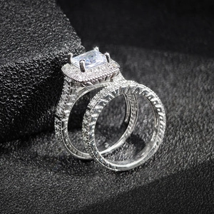 Vista macro de conjunto de anillos de plata con diamante corte esmeralda y halo