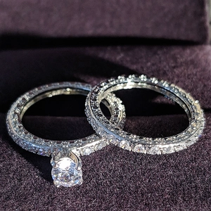Close-up of sparkling solitaire and pave wedding ring set on purple velvet
