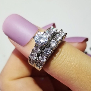 Macro detail of a silver couple's wedding ring set with large round center stone and pave diamonds
