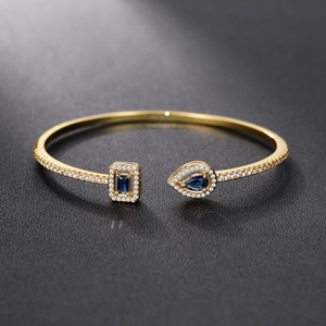 Detail of a 18K gold-plated open bracelet with sapphire blue stones and micro-pave setting