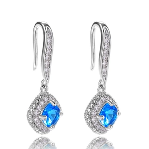 Detail view of silver drop earrings with square blue gemstone and diamond halo setting