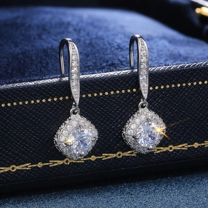Macro shot of silver halo drop earrings with square cubic zirconia on blue velvet