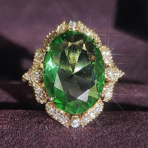 Vue détaillée d'une bague avec zircon vert ovale, monture dorée et fond en velours
