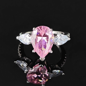 Macro d'une bague avec gemme rose taille poire et deux pierres latérales blanches