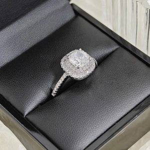Détail d'une bague en zircone taille coussin avec double halo et pavé sur cuir noir