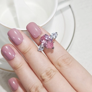 Gros plan d'une bague goutte rose en argent portée sur la main avec un vernis assorti
