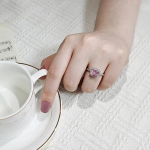 Macro view of square pink gemstone ring with halo diamonds on model hand