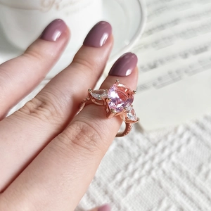 Vue détaillée d'une bague en or rose avec gemme rose taille poire portée au doigt
