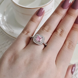 Gros plan d'une bague en argent avec zircon rose et double halo de diamants pavés
