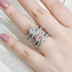 Macro detail of intertwined silver rings with round white and pink stones on hand