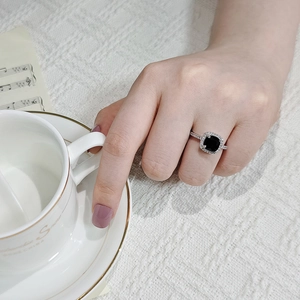 Detailed view of luxury square black gemstone ring with halo setting on a model hand